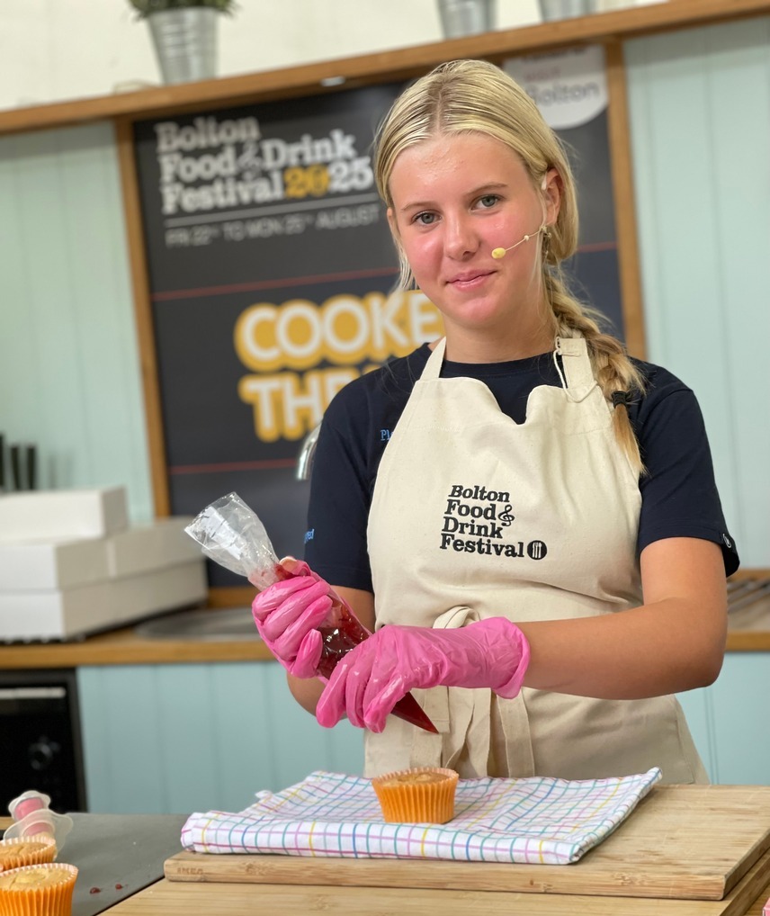 Young chef piping some icing onto a cake